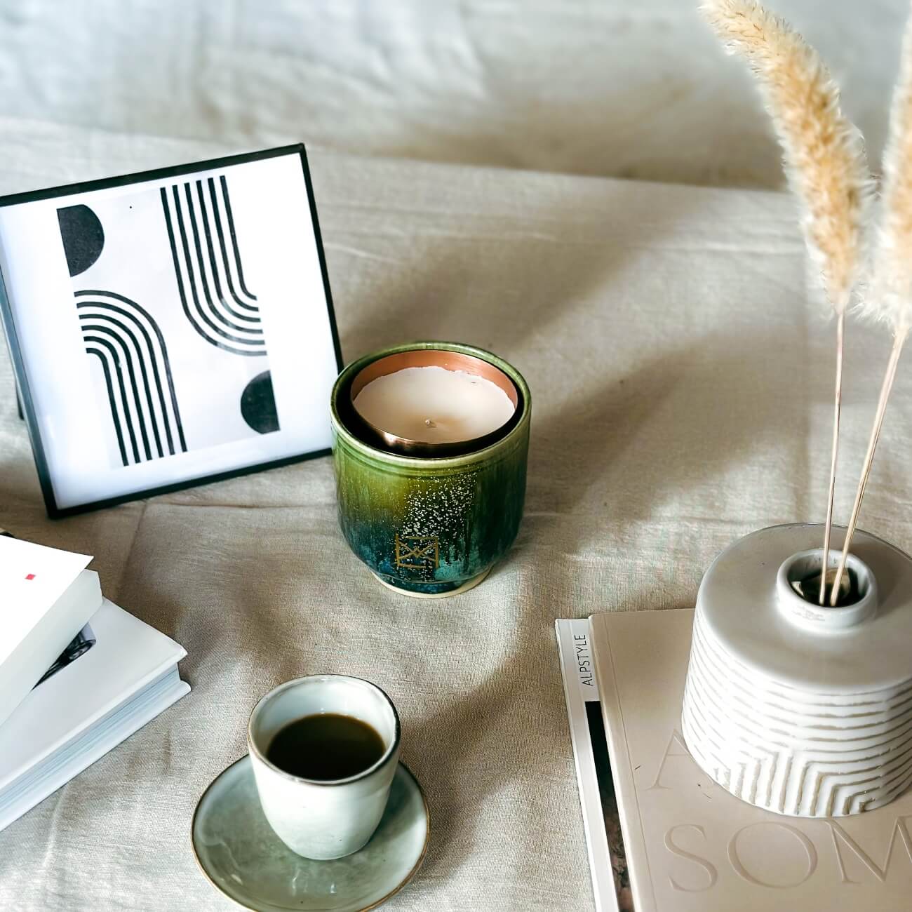 Bougie parfumée écologique dans un pot en céramique, entourée de décorations minimalistes et d'un café sur une table en lin naturel.