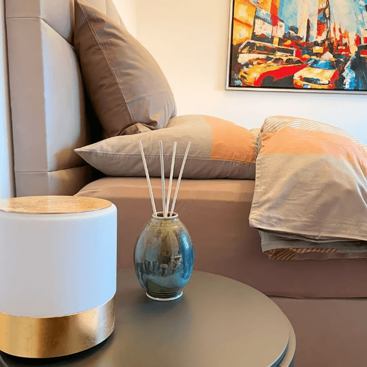 Diffuseur de parfum à rotin élégant sur table basse dans une chambre à coucher moderne, parfait pour une nuit relaxante et reposante.