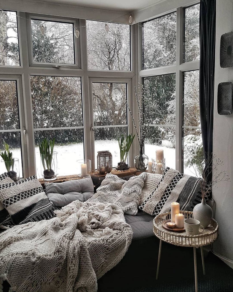 Un canapé vétu de couvertures et de coussins à long poils s'étant devant une baie vitreé en montagne. Dehors, la neige tomber et seul le son du bois qui crépite dans la cheminée se fait entendre. Un parfum de canelle sucré et des arômes boisée enveloppe l'atmosphère. C'est la fragrance Neige Ardente de Erra. Disponible en diffuseur et bougie.